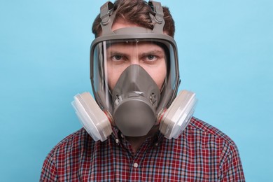 Man in respirator mask on light blue background