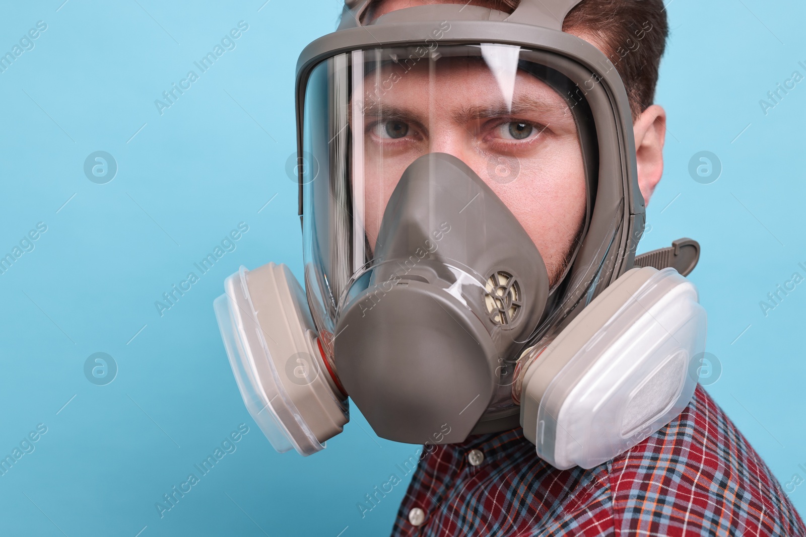 Photo of Man in respirator mask on light blue background