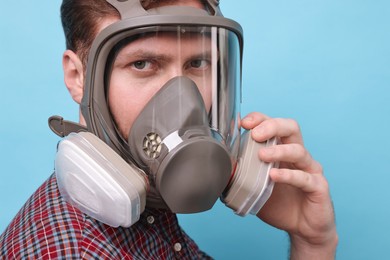 Man in respirator mask on light blue background