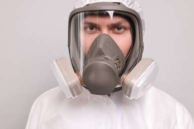 Man wearing protective suit with respirator mask on light background