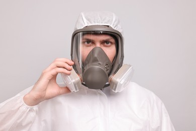 Photo of Man wearing protective suit with respirator mask on light background