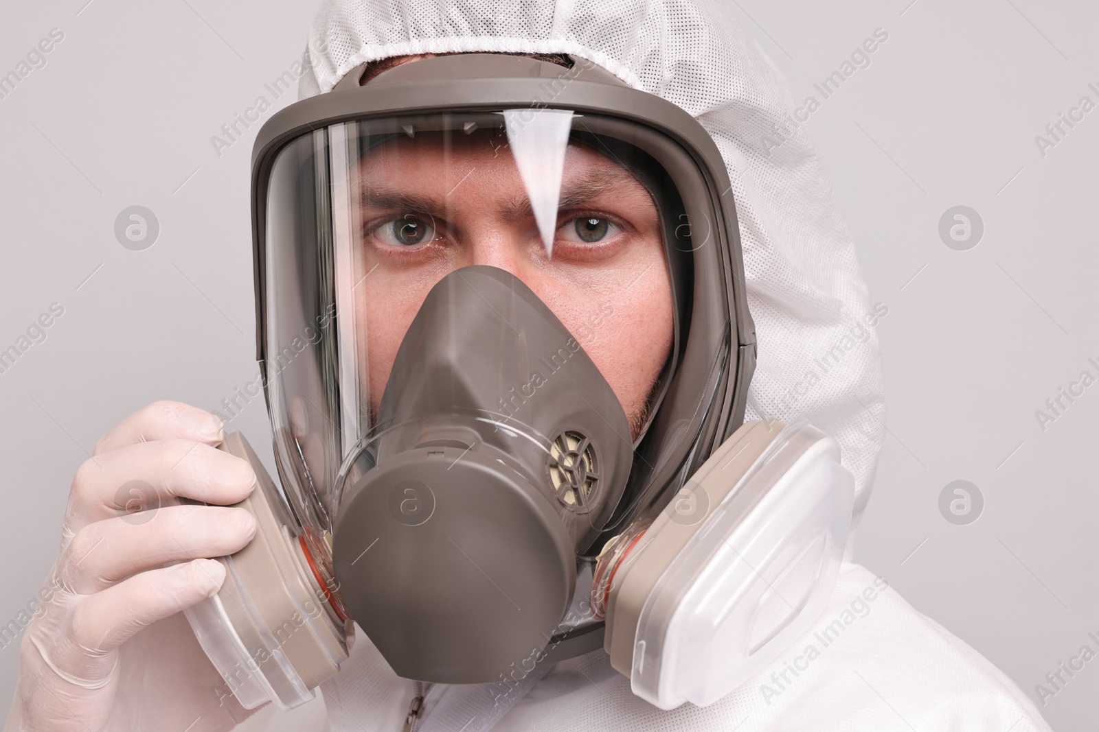 Photo of Man wearing protective suit with respirator mask on light background