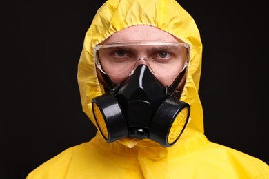 Photo of Man wearing protective suit with respirator mask on black background