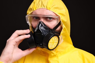 Photo of Man wearing protective suit with respirator mask on black background