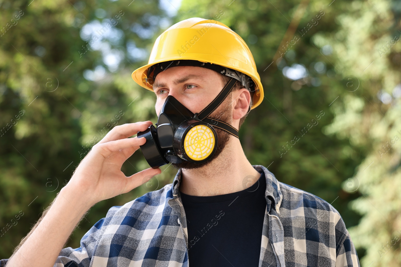 Photo of Man in respirator mask and hard hat outdoors. Safety equipment