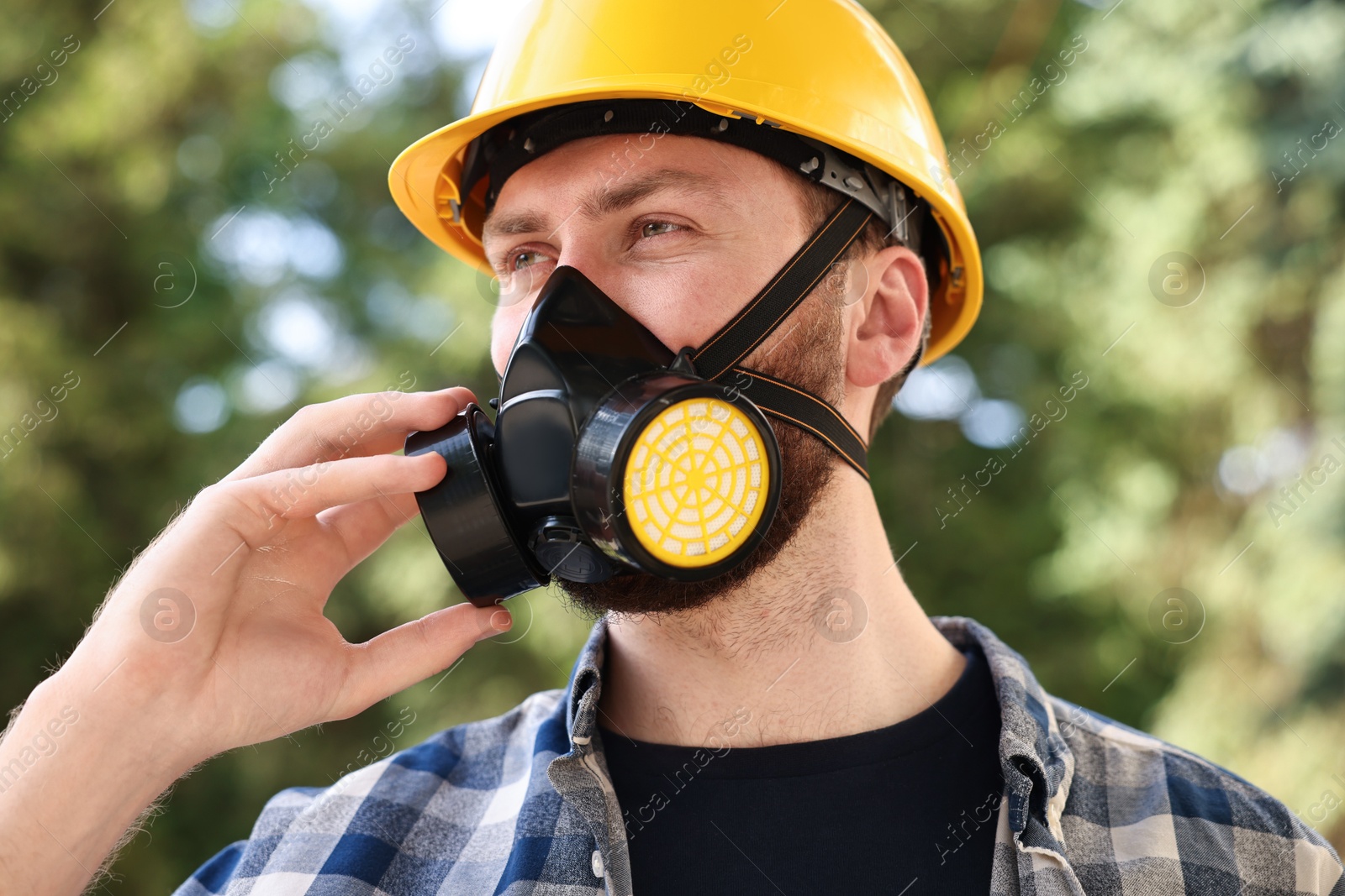 Photo of Man in respirator mask and hard hat outdoors. Safety equipment