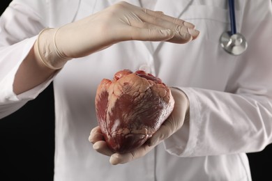 Photo of Doctor with heart on black background, closeup