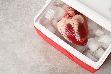 Photo of Heart with ice in cool box on grey table, top view. Space for text