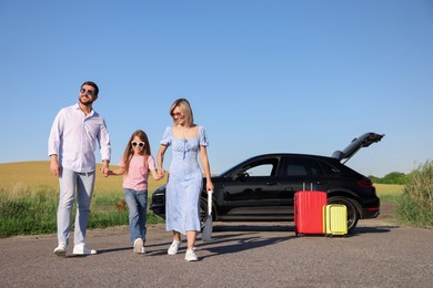 Parents, their daughter, car and suitcases outdoors. Family traveling