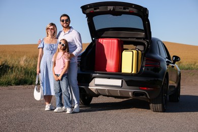 Happy family near car with suitcases outdoors