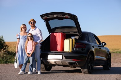 Happy family near car with suitcases outdoors