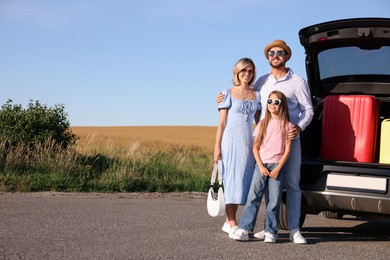 Happy family near car with suitcases outdoors, space for text