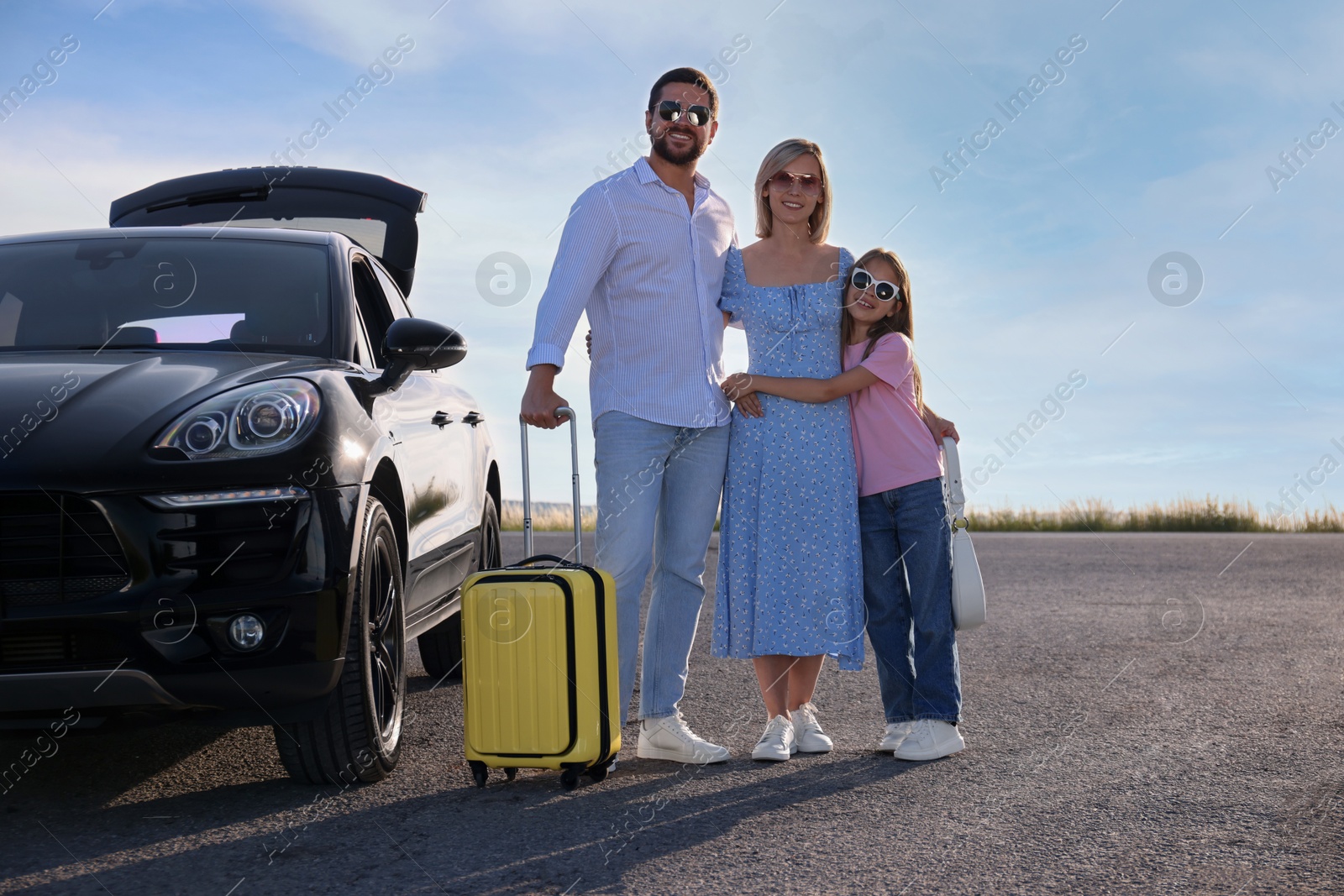 Photo of Happy family with suitcase near car outdoors