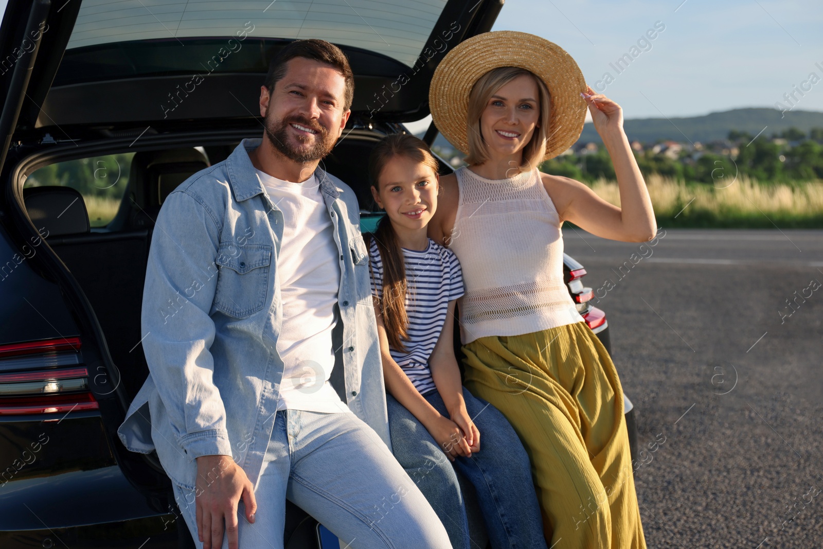 Photo of Happy family sitting in trunk of car outdoors