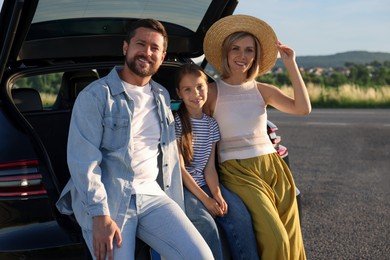 Happy family sitting in trunk of car outdoors