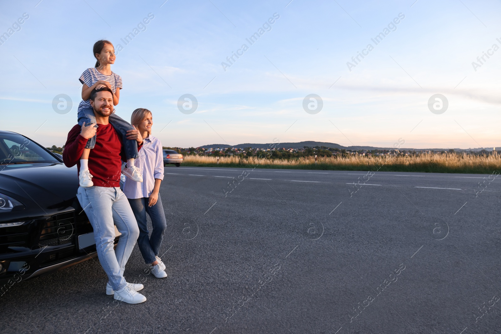 Photo of Happy parents and their daughter near car outdoors, space for text