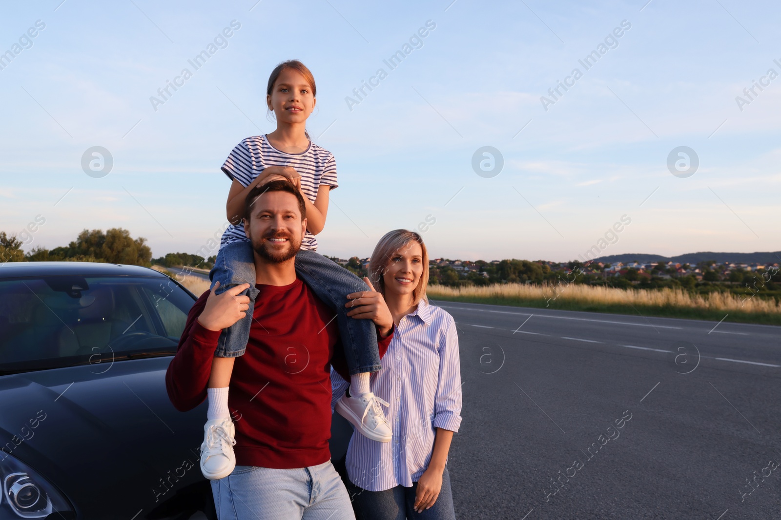 Photo of Happy parents and their daughter near car outdoors, space for text