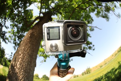 Man with modern action camera and monopod outdoors, closeup. Fisheye lens effect