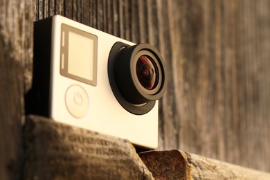 Modern action camera on wooden surface, closeup. Space for text