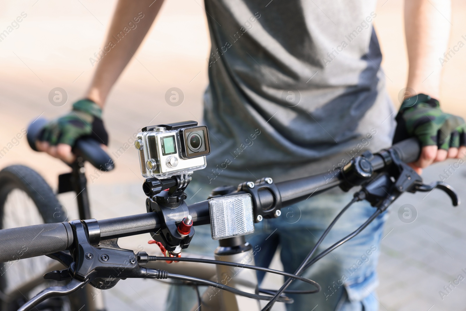 Photo of Man near bicycle with modern action camera outdoors, closeup