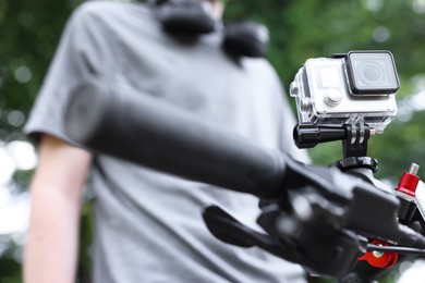 Photo of Man near bicycle with modern action camera outdoors, closeup