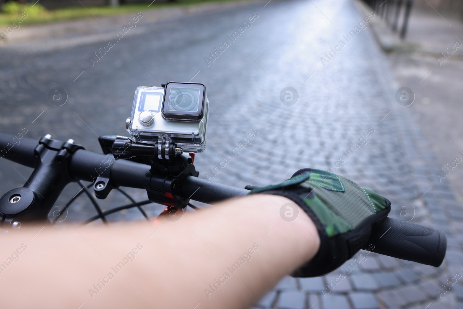 Photo of Man riding bicycle with modern action camera outdoors, closeup