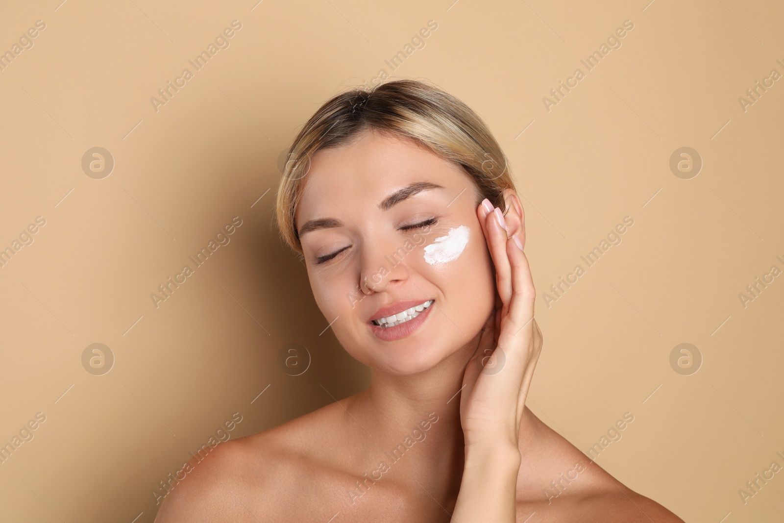 Photo of Beautiful woman with cream on her face against beige background