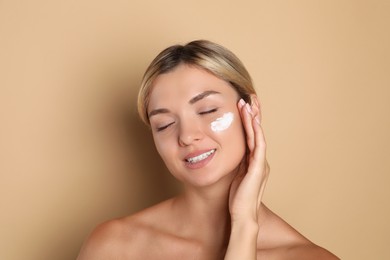 Beautiful woman with cream on her face against beige background