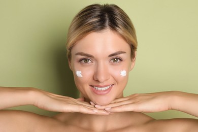 Photo of Beautiful woman with cream on her face against green background