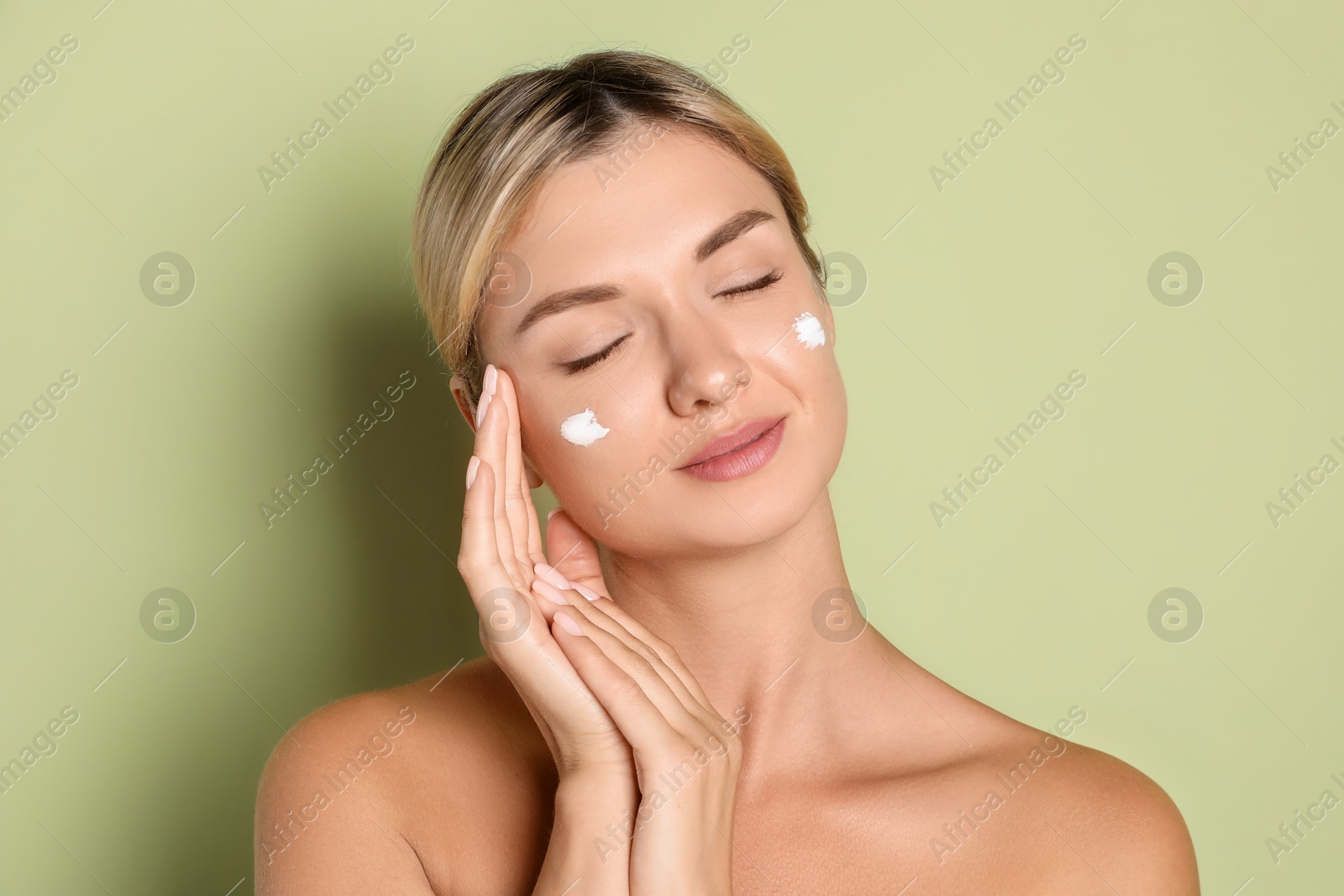 Photo of Beautiful woman with cream on her face against green background