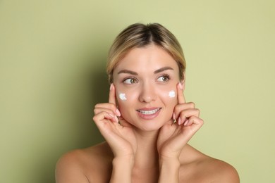 Beautiful woman with cream on her face against green background