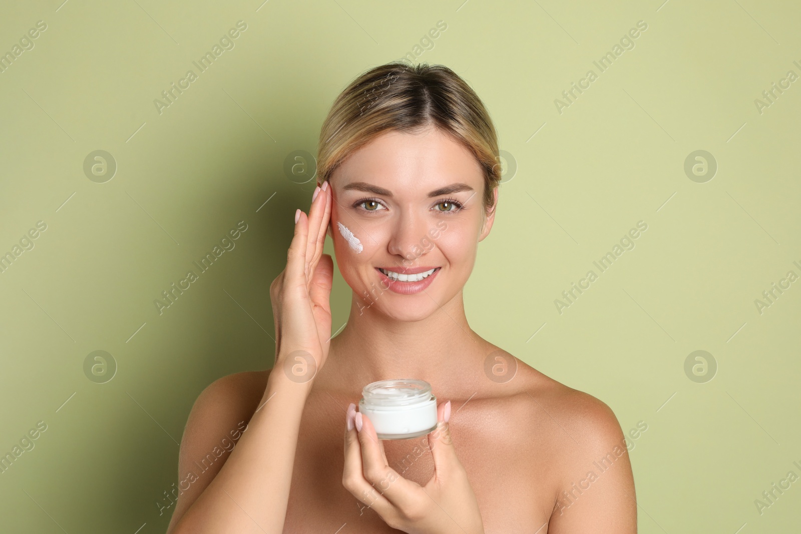 Photo of Beautiful woman with jar of facial cream against green background