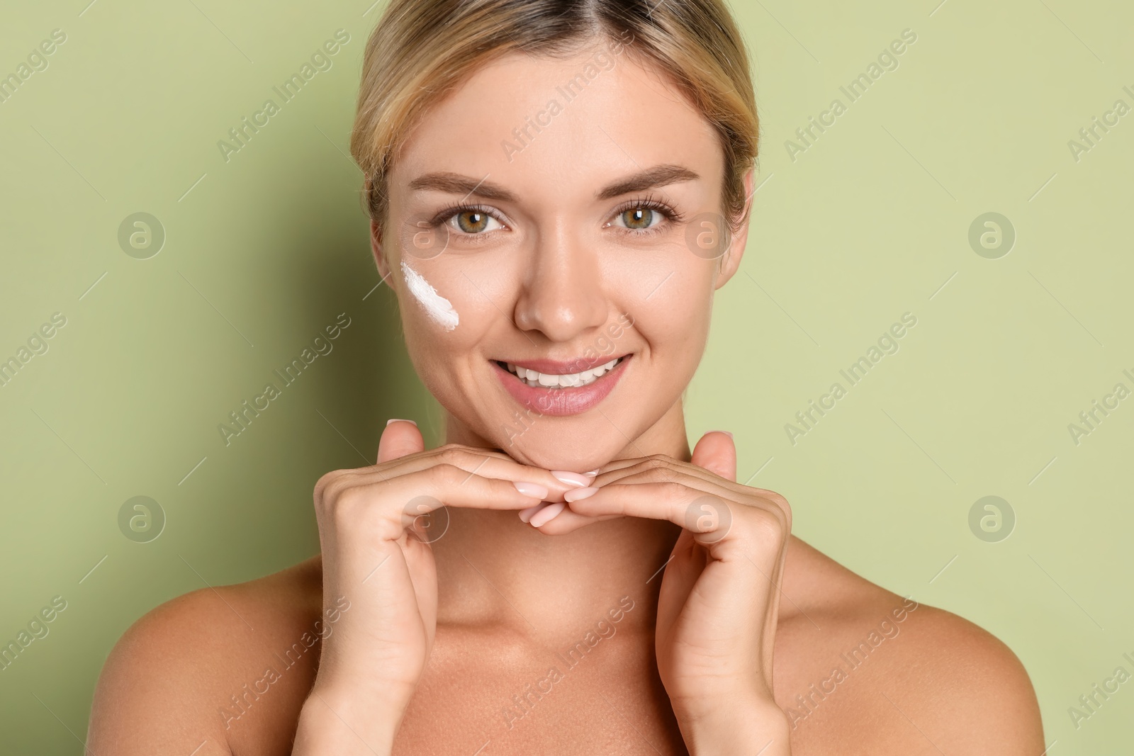 Photo of Beautiful woman with cream on her face against green background