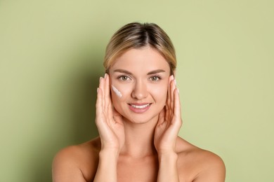 Photo of Beautiful woman with cream on her face against green background