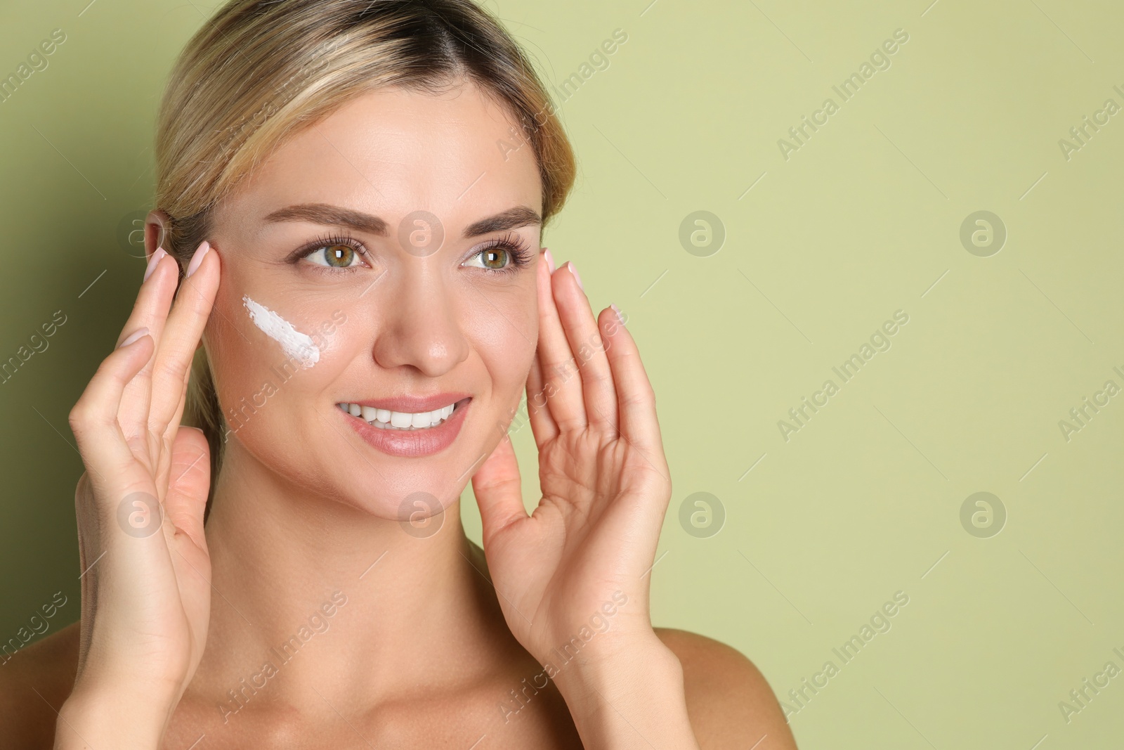 Photo of Beautiful woman with cream on her face against green background, space for text