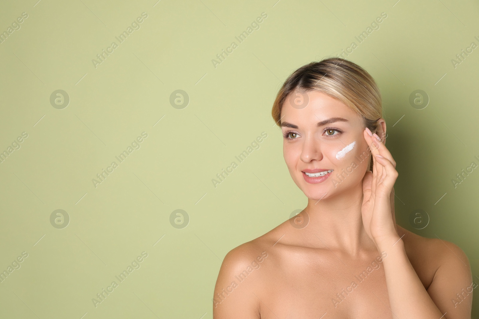 Photo of Beautiful woman with cream on her face against green background, space for text