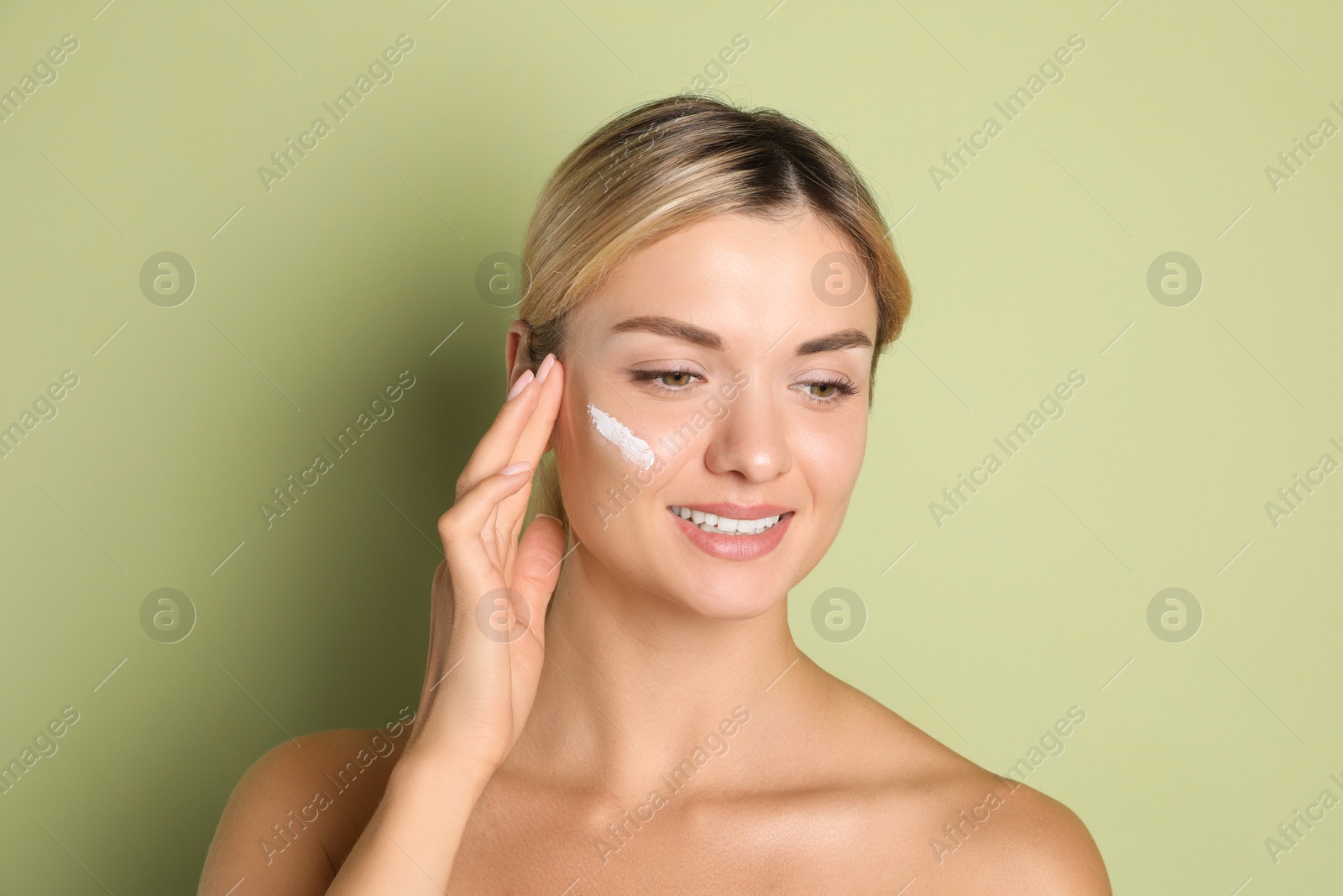 Photo of Beautiful woman with cream on her face against green background