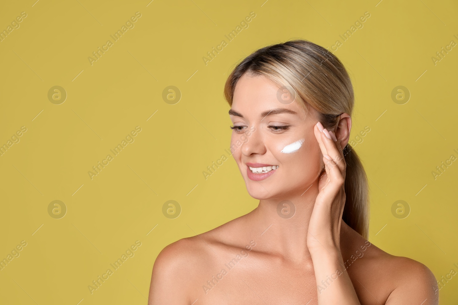 Photo of Beautiful woman with cream on her face against olive background, space for text