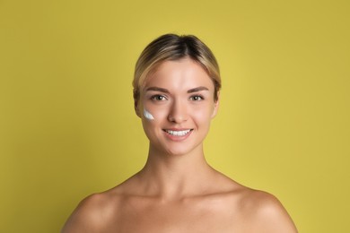 Beautiful woman with cream on her face against olive background