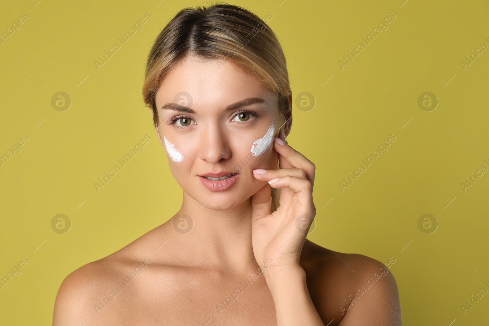 Photo of Beautiful woman with cream on her face against olive background