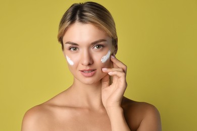 Beautiful woman with cream on her face against olive background