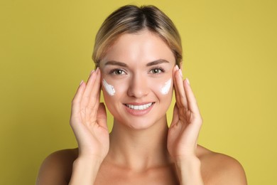 Photo of Beautiful woman with cream on her face against olive background