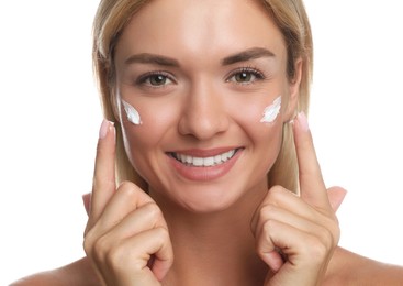 Beautiful woman applying face cream on white background