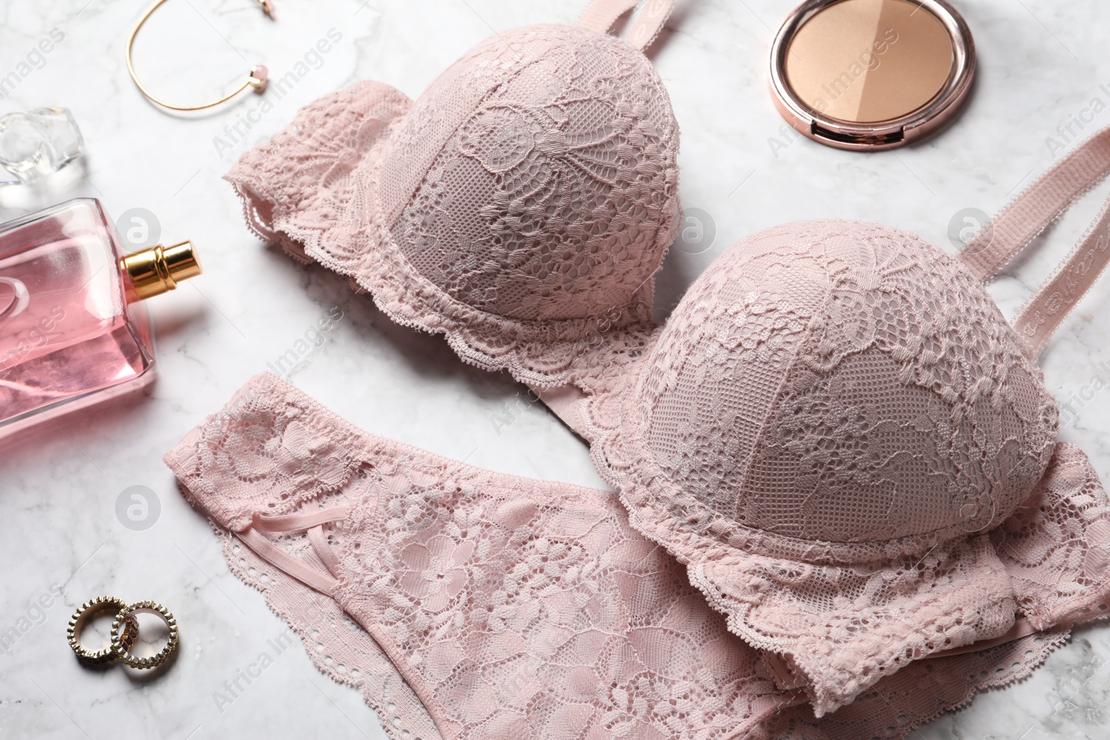 Photo of Beautiful lace lingerie set and accessories on light marble background, closeup