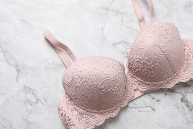 Photo of Beautiful lace bra on light marble background, top view