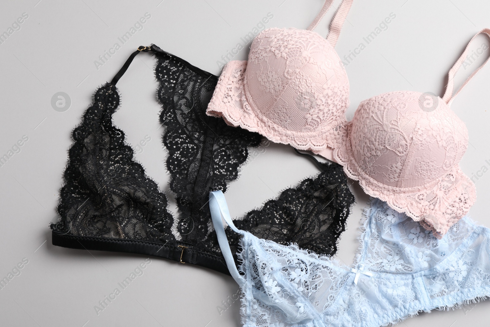 Photo of Different lace bras on grey background, top view