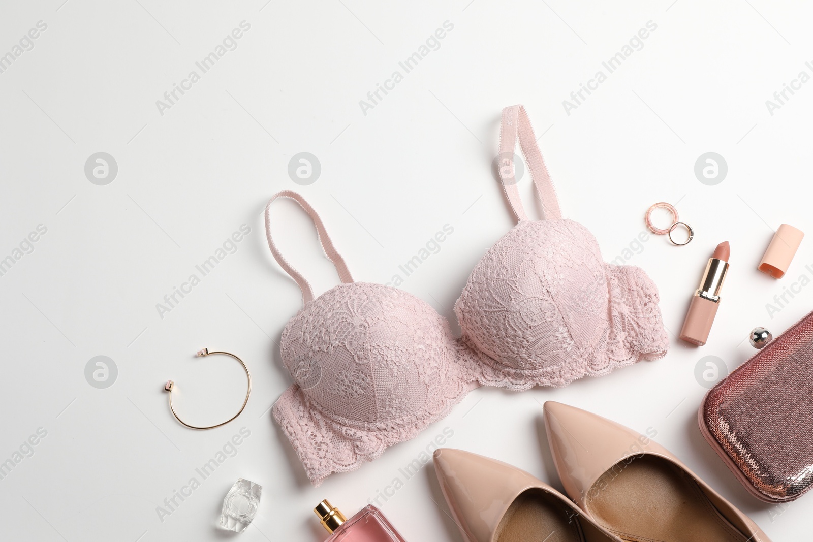 Photo of Beautiful lace bra and accessories on white background, flat lay