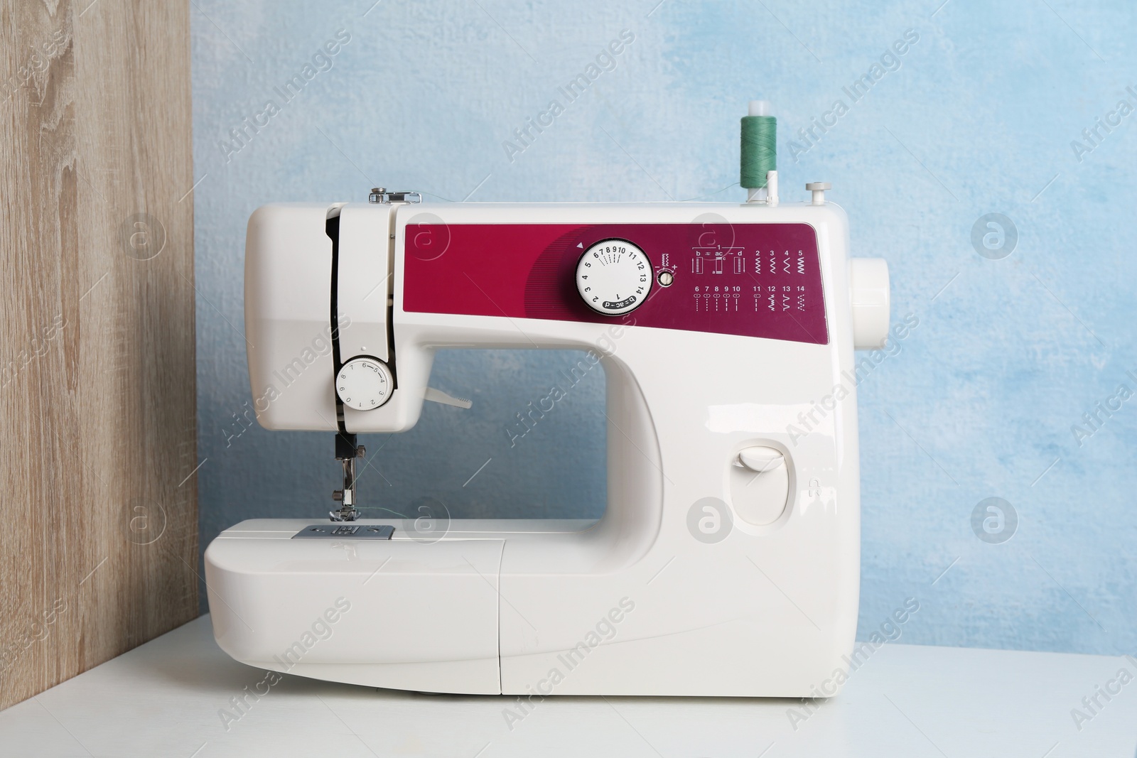 Photo of Sewing machine on white table near light blue wall indoors