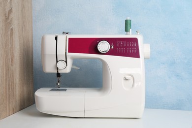 Photo of Sewing machine on white table near light blue wall indoors