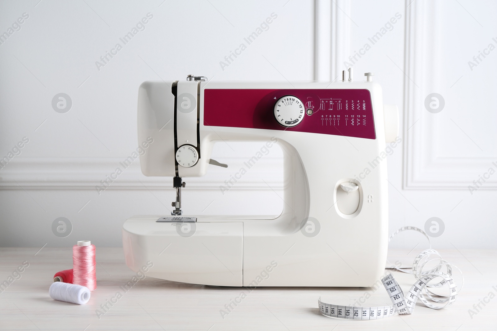 Photo of Sewing machine and craft accessories on white wooden table indoors